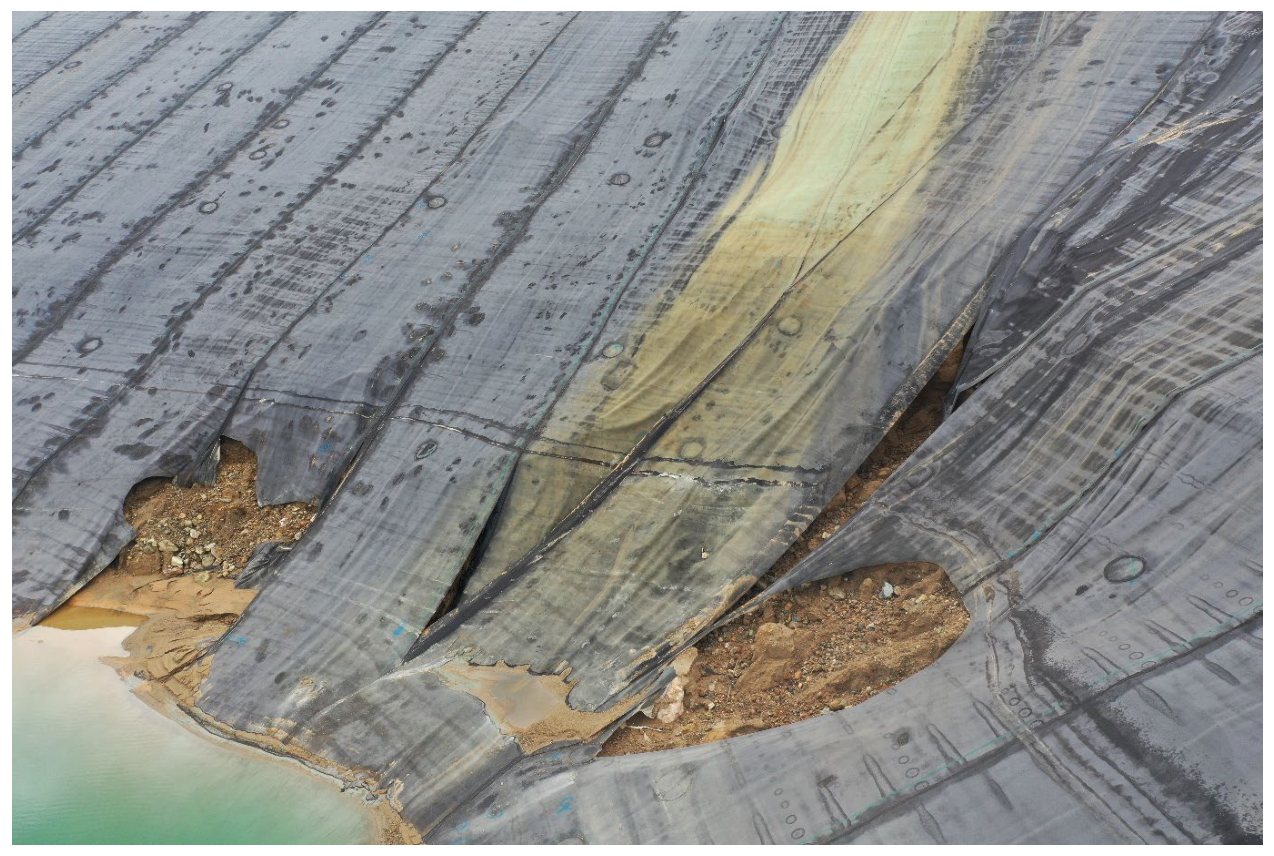 Degradation at the toe of the embankment, with liner tearing and exposed fill material